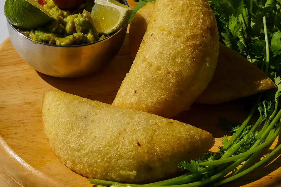Une empanada sur une planche en bois, avec de la coriandre